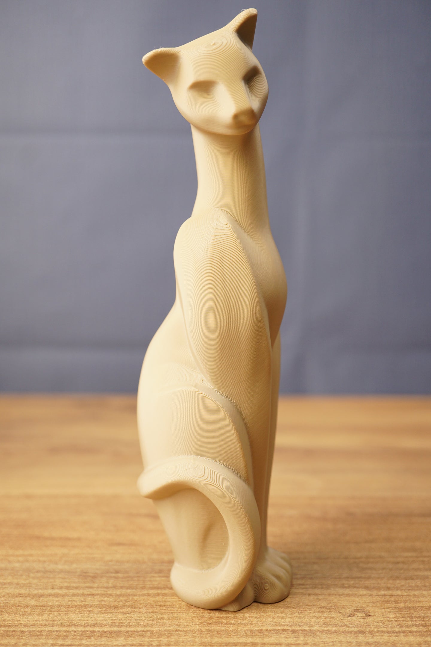 Tall Tarkov inspired cat figurine replica displayed on a wooden tabletop, with beige finish, elegant seated pose, and curved tail design.