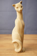 Tall Tarkov inspired cat figurine replica displayed on a wooden tabletop, with beige finish, elegant seated pose, and curved tail design.