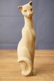 Tall Tarkov inspired cat figurine replica displayed on a wooden tabletop, with beige finish, elegant seated pose, and curved tail design.