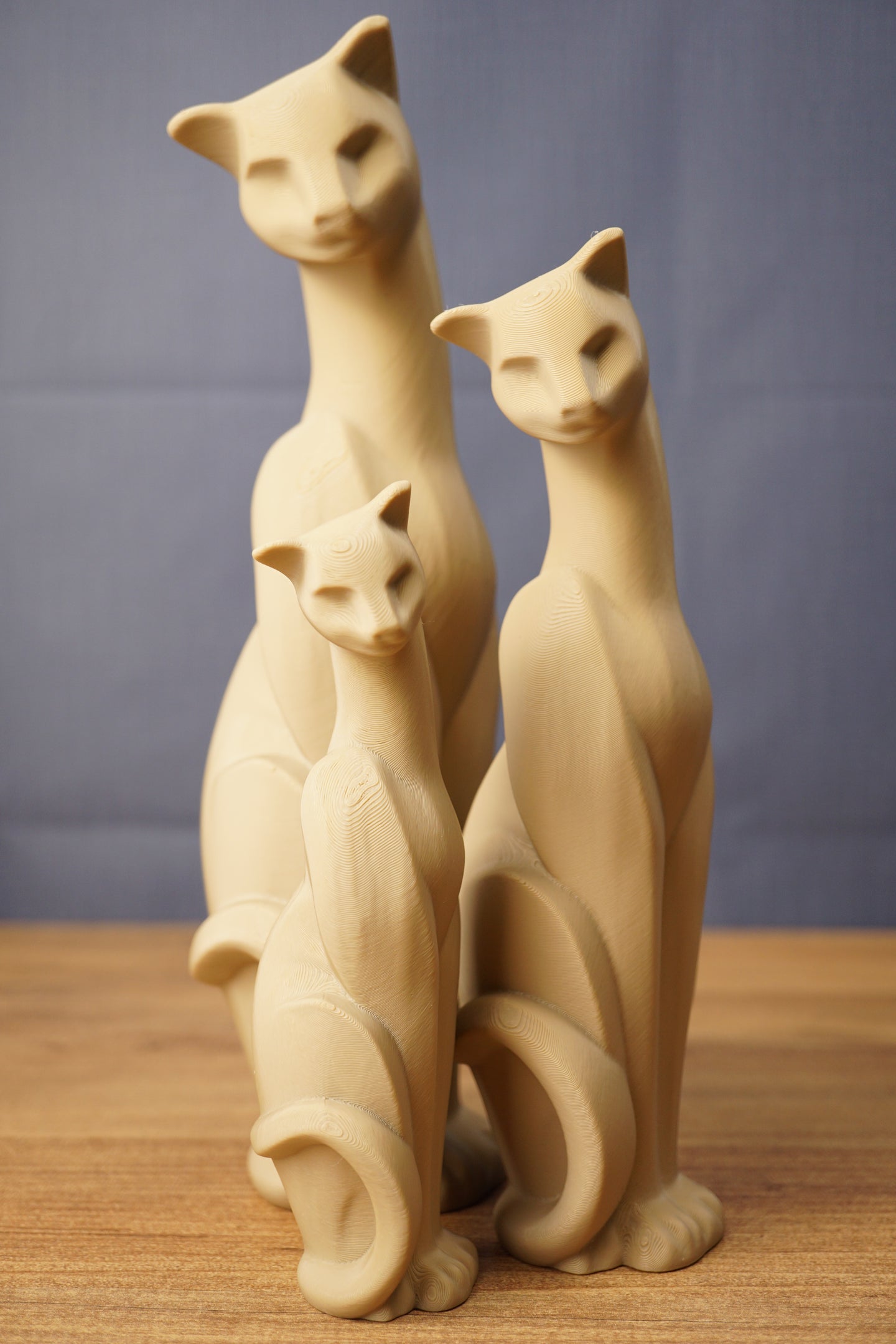 Set of three beige 3D printed cat figurines inspired by Tarkov, displayed together on a wooden tabletop with a grey backdrop.
