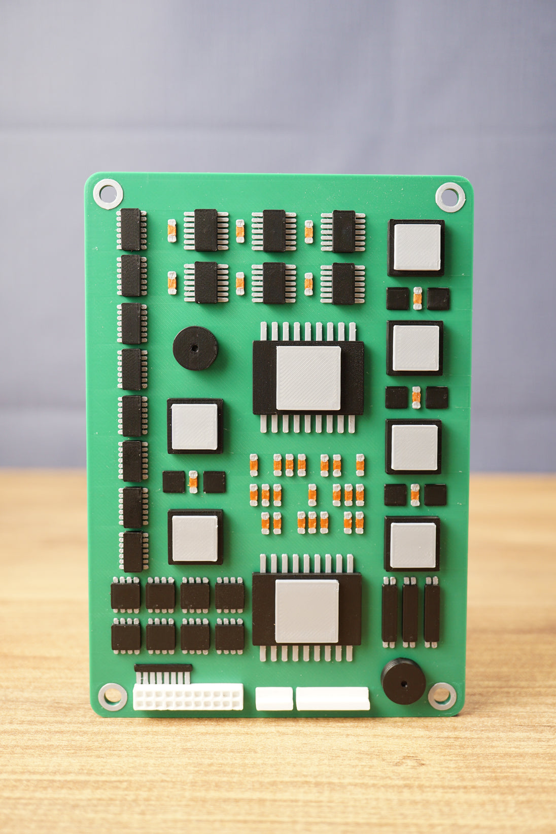 Front view of a military circuit board replica with detailed chips, silver raised parts, orange component accents, and rounded corner mounting holes.