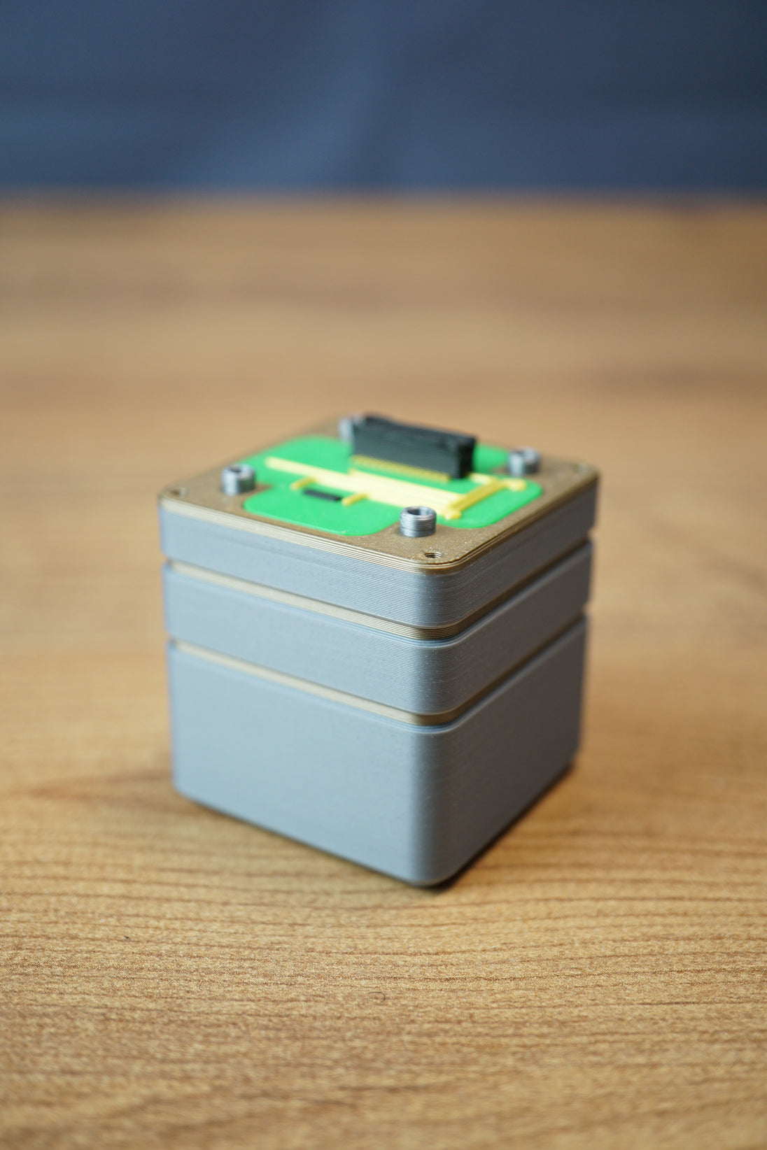Angled view of an Iridium thermal vision module replica with layered grey casing, green circuit top plate, and compact display prop design.