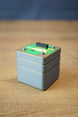Angled view of an Iridium thermal vision module replica with layered grey casing, green circuit top plate, and compact display prop design.