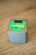 Top view of an Iridium thermal vision module replica prop with green circuit detail, grey casing, corner screw accents, and black connector.