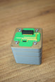 Top view of an Iridium thermal vision module replica prop with green circuit detail, grey casing, corner screw accents, and black connector.