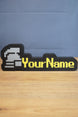 Ultimate ironman RuneScape-style nameplate with a silver helmet icon, bright yellow custom text, and black border displayed on a desk.