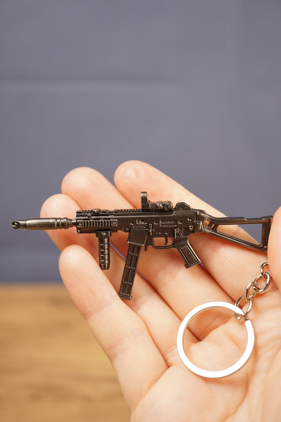 UMP45-style metal gun keyring resting in hand with attached key loop, ideal as an FPS gamer gift or tactical shooter accessory