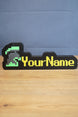 Personalized RuneScape-style nameplate featuring an unranked group ironman helmet icon with green and grey detailing and yellow custom lettering on a desk.