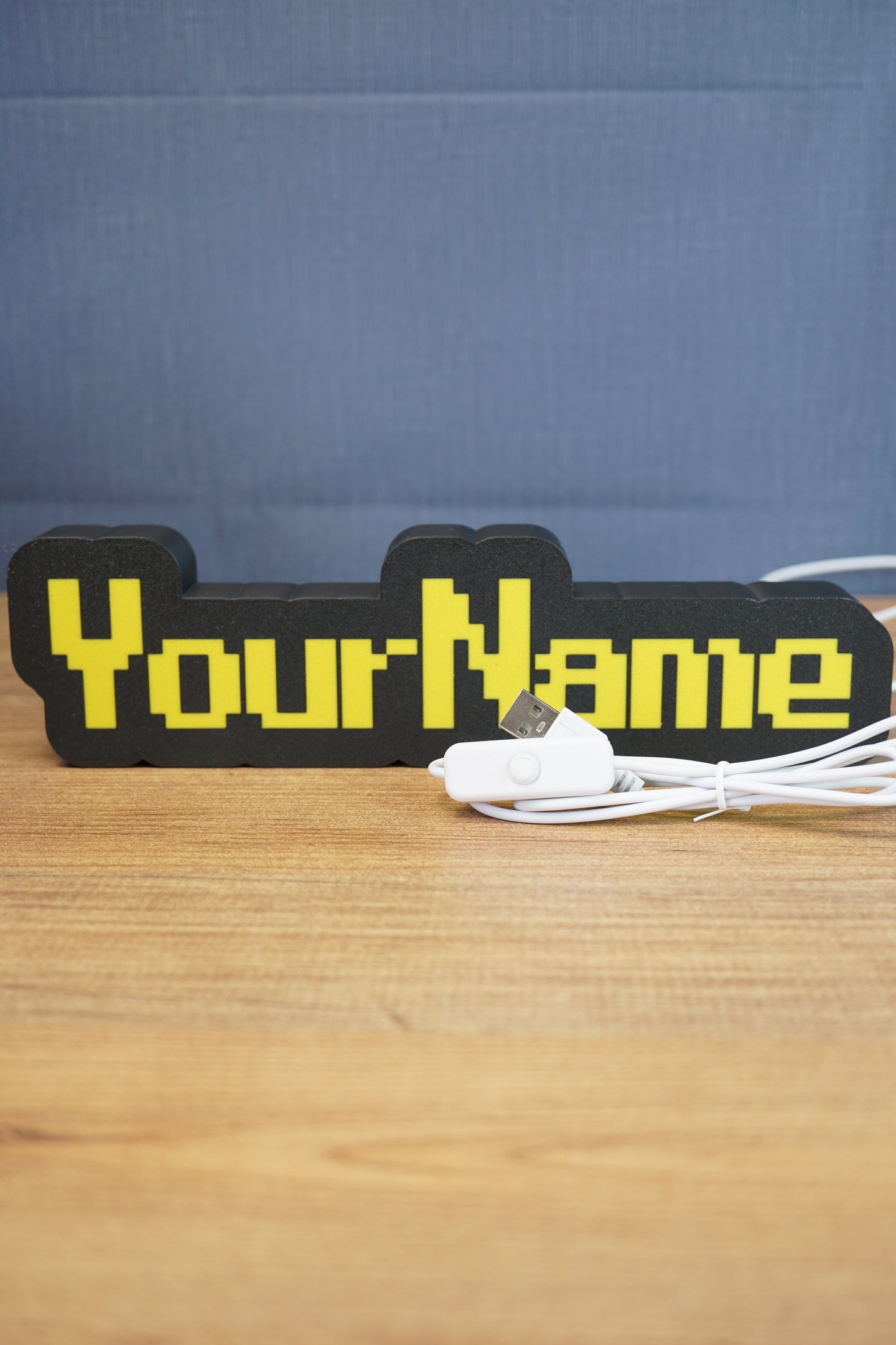 Custom USB-powered YourName LED sign with RuneScape-style font, yellow lettering, and black casing on a wooden desk.