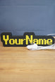 Custom USB-powered YourName LED sign with RuneScape-style font, yellow lettering, and black casing on a wooden desk.