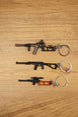 Three VSS Vintorez and AS Val style rifle keychains displayed on a wooden surface, showing base, modded and scoped tactical variants