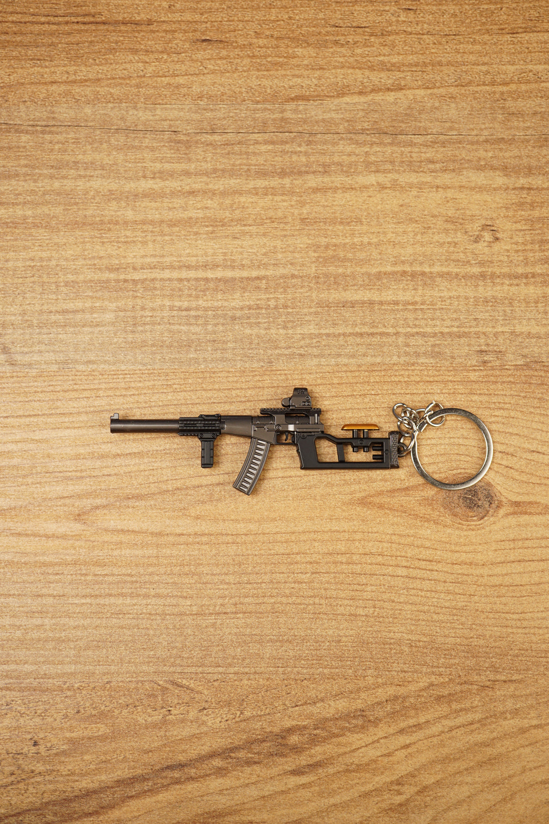 VSS Vintorez style rifle keychain with suppressor, curved magazine and tactical stock displayed flat on a wooden background