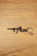 VSS Vintorez style rifle keychain with suppressor, curved magazine and tactical stock displayed flat on a wooden background