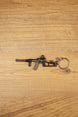 VSS Vintorez style rifle keychain with suppressor, curved magazine and tactical stock displayed flat on a wooden background