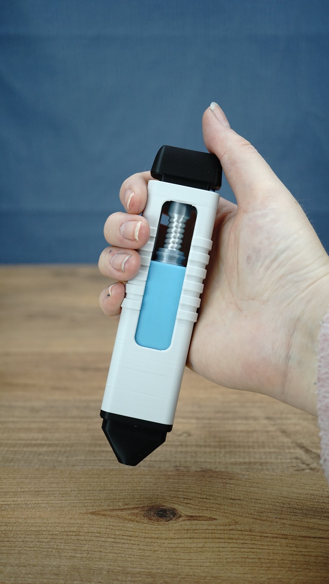 WARDOGS Adrenaline Pen clicker fidget toy held in hand, showing the 16cm white and black body, blue insert and exposed mechanical design.