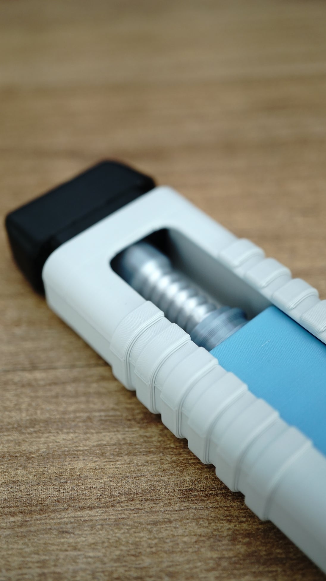 Close-up of the WARDOGS Adrenaline Pen fidget toy showing its exposed silver mechanical clicker mechanism, blue insert and textured white grip.