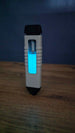 WARDOGS Adrenaline Pen replica standing upright on a wooden table in low light, showing the glowing blue panel, white grip and visible silver mechanism.