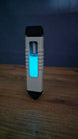 WARDOGS Adrenaline Pen replica standing upright on a wooden table in low light, showing the glowing blue panel, white grip and visible silver mechanism.