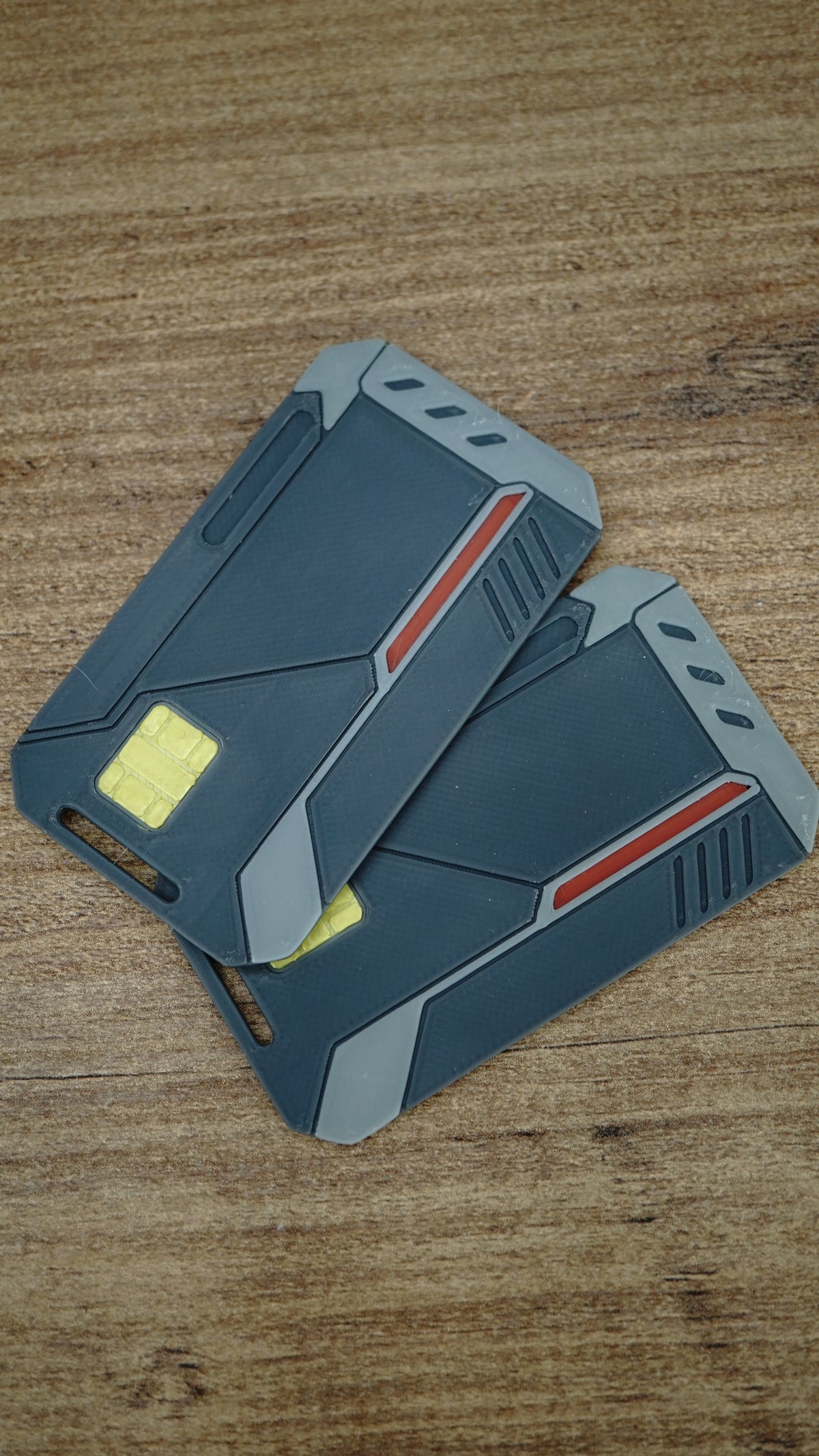 Two WARDOGS Alpha Card 1 keycard replicas stacked together, showing the futuristic grey panels, yellow chip features and red accent details.