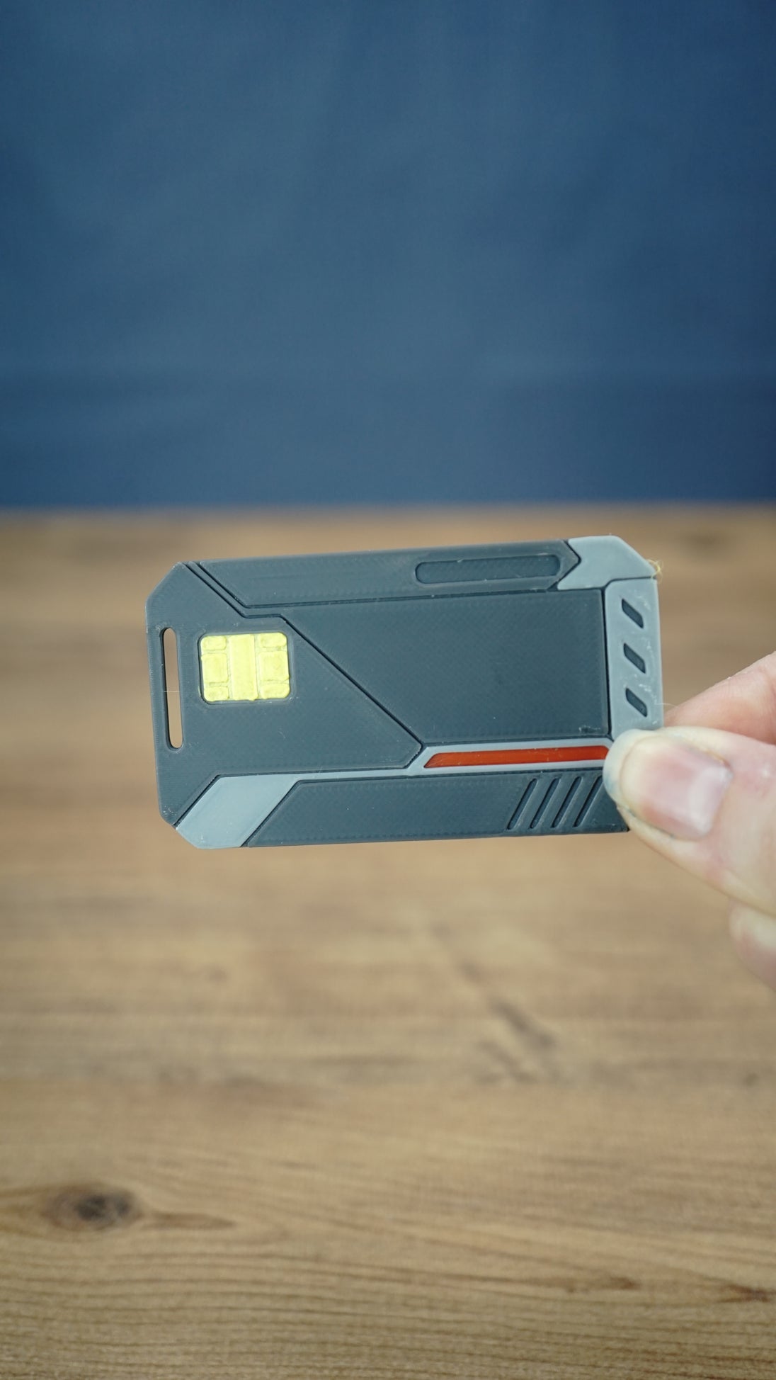 WARDOGS Alpha Card 1 replica held between fingers to demonstrate its compact 7 cm length, with the tactical-style design clearly visible.