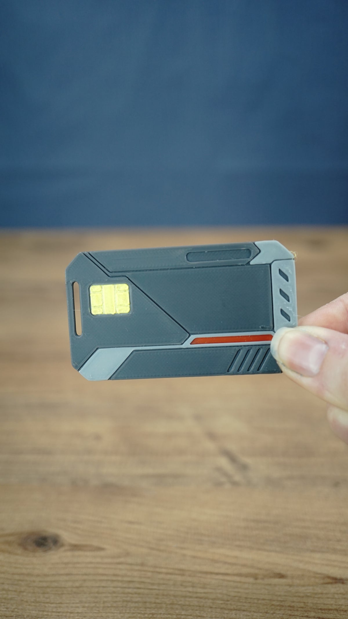 WARDOGS Alpha Card 1 replica held between fingers to demonstrate its compact 7 cm length, with the tactical-style design clearly visible.