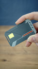 Angled handheld view of the WARDOGS Alpha Card 1 collectible replica featuring a yellow chip design, grey corner details and red accent stripe.