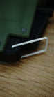 Detailed close-up of the silver loop on the WARDOGS remote detonator replica, beside its black housing and olive green shell.