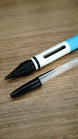 WARDOGS Adrenaline Stim Pen replica with fitted ballpoint writing tip exposed, positioned beside a transparent BIC-style pen for comparison.