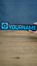 Lonestar Blue 25cm gaming nameplate held in one hand, featuring raised blue YOURNAME lettering and the blue star emblem on a black base.