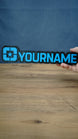 Lonestar Blue 25cm gaming nameplate held in one hand, featuring raised blue YOURNAME lettering and the blue star emblem on a black base.