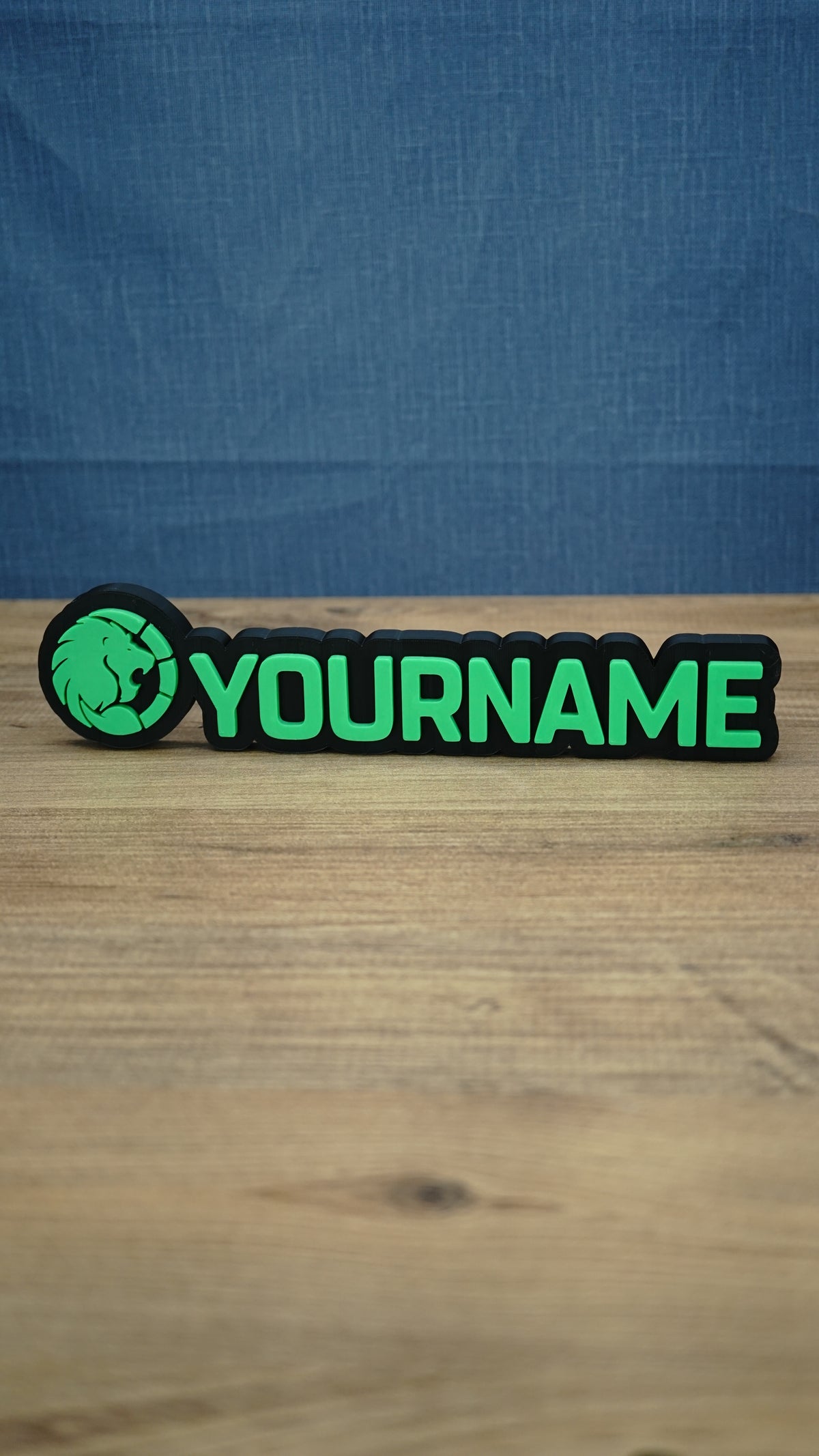 Front view of a WARDOGS-inspired Manticore Green gaming nameplate with bright green YOURNAME lettering, a lion emblem and a contrasting black base.