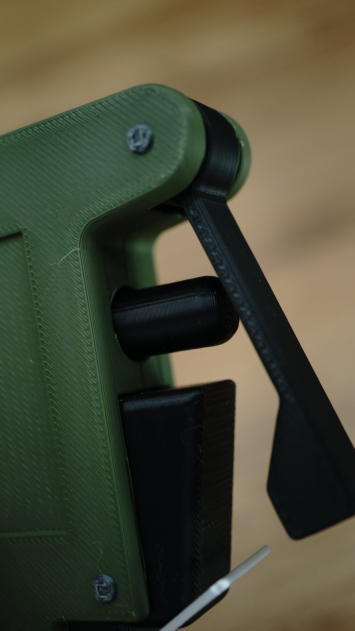Close-up of the WARDOGS remote detonator replica's black pivoting side lever and cylindrical fidget control against its green casing.