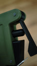 Close-up of the WARDOGS remote detonator replica's black pivoting side lever and cylindrical fidget control against its green casing.