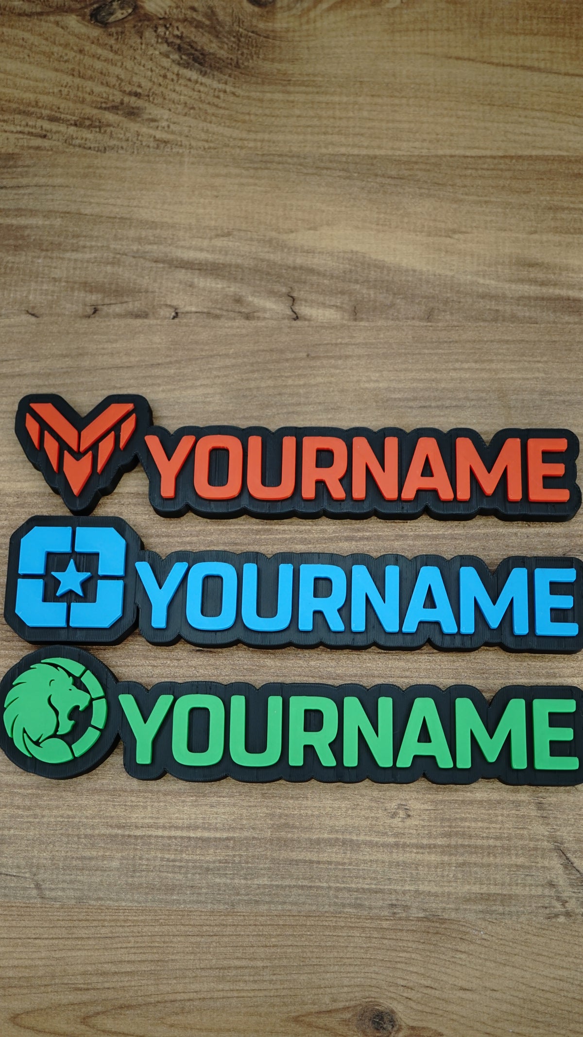 Three WARDOGS-inspired gaming nameplates arranged horizontally, showing Valkyra Red, Lonestar Blue and Manticore Green faction designs with YOURNAME text.
