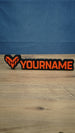 WARDOGS-inspired Valkyra Red gaming nameplate featuring raised red-orange YOURNAME lettering, an angular faction emblem and a black base.