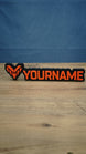 WARDOGS-inspired Valkyra Red gaming nameplate featuring raised red-orange YOURNAME lettering, an angular faction emblem and a black base.